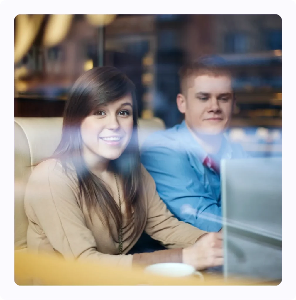 A smiling girl is sitting next to a boy wearing a blue coat.